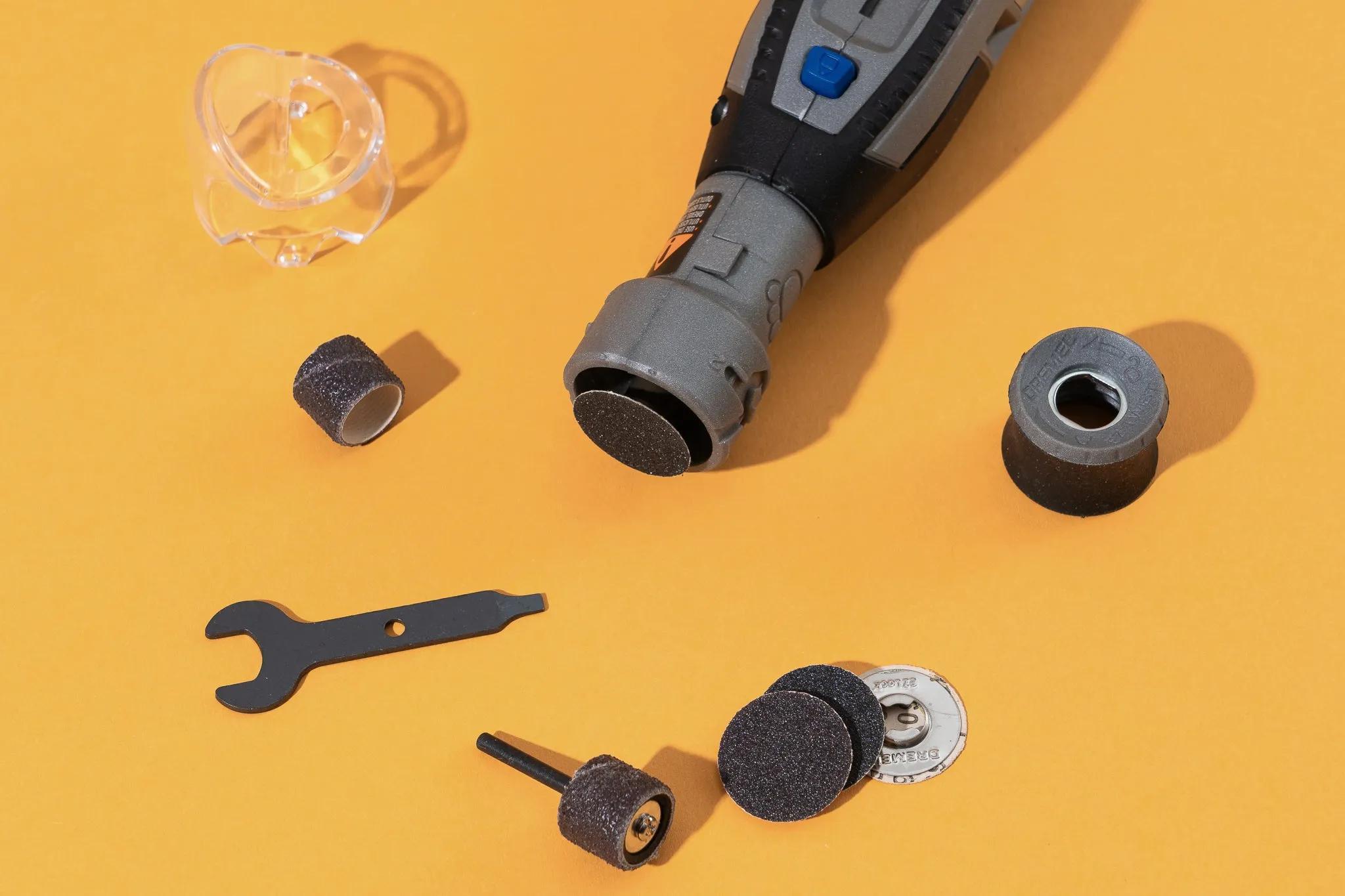 The top of the Dremel grinder with several attachments and accessories surrounding it.