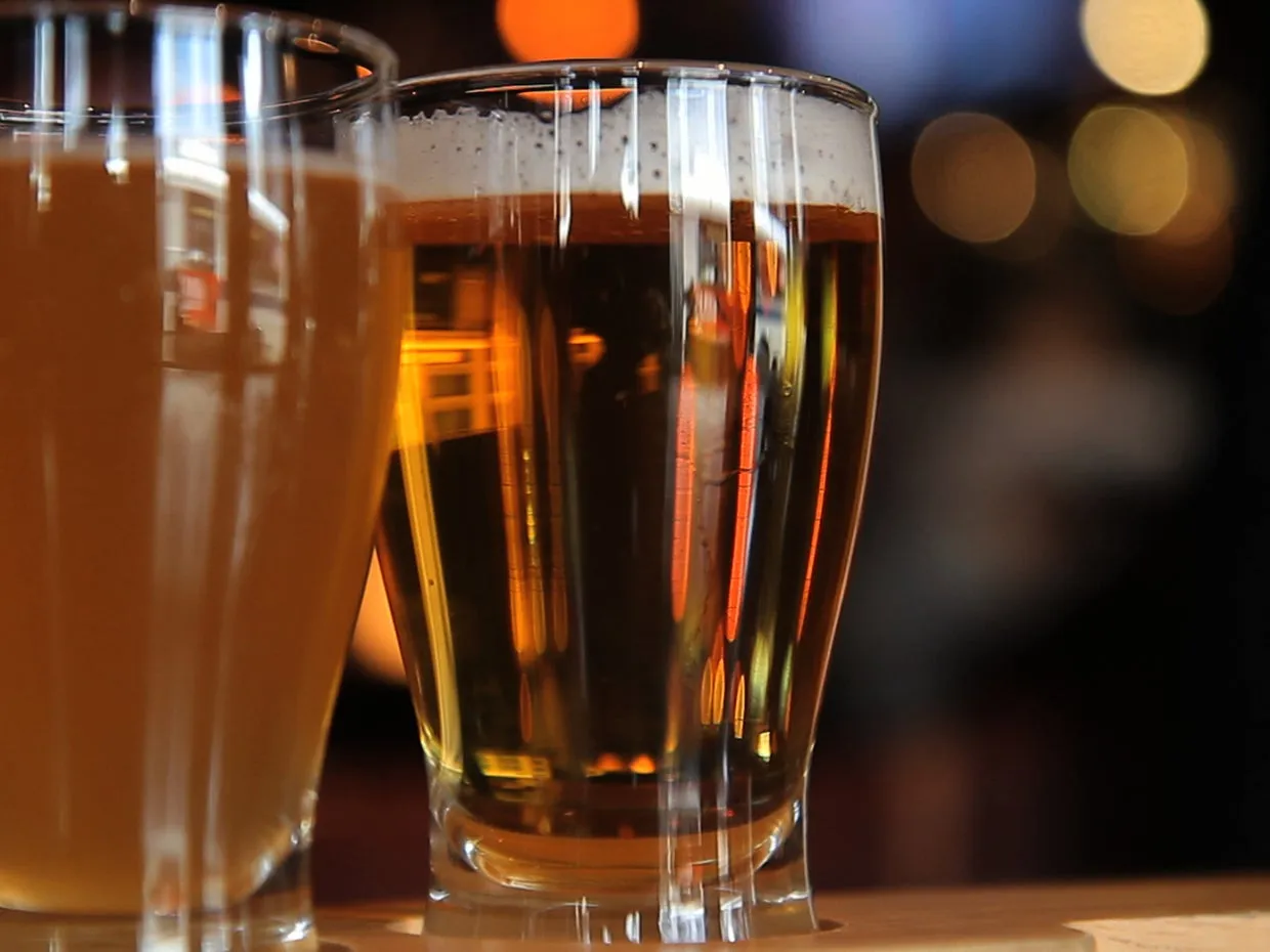 Two bottles of beer and a glass of beer with foam, illustrating alcoholic beverages.