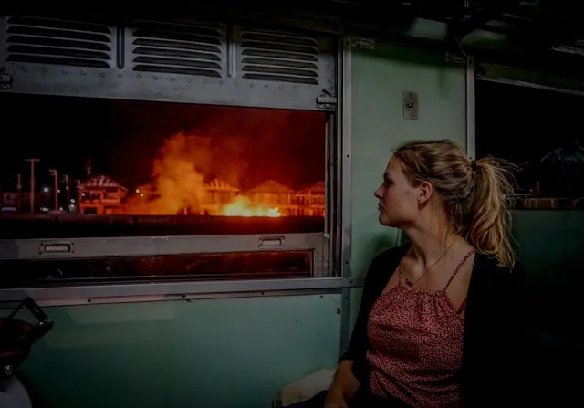 A woman looks out a window at a fire