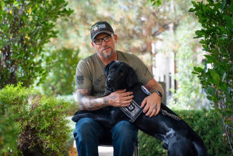 A person experiencing anxiety sitting on the floor while their golden retriever service dog performs Deep Pressure Therapy by laying across their lap.