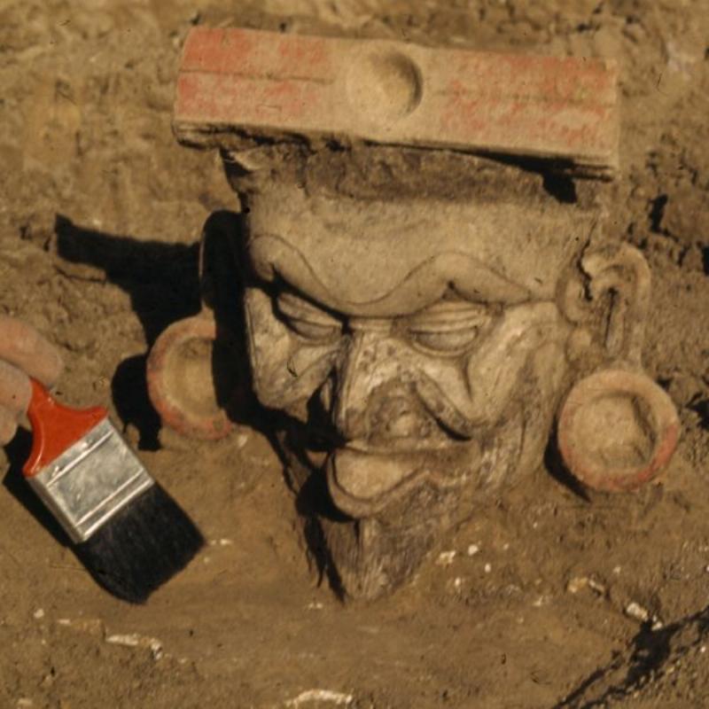 Archaeologists carefully brushing away dirt from ancient stone ruins at the Hisarlik excavation site, representing the search for the real Troy.