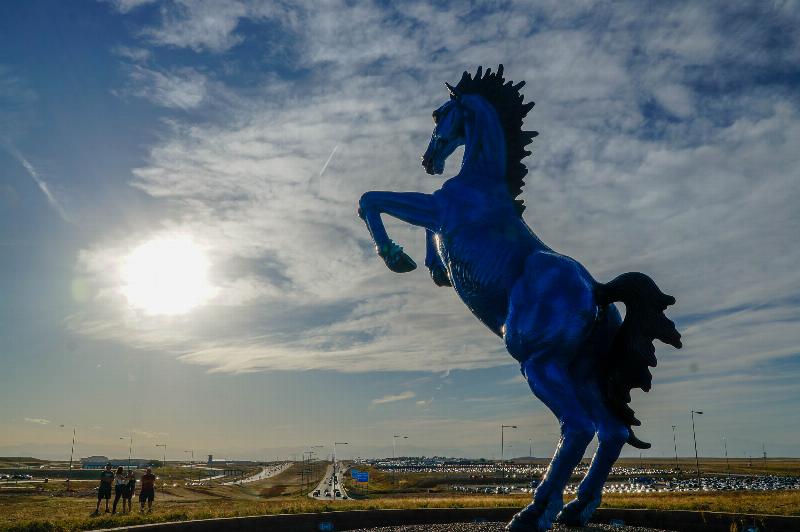 The giant blue horse statue known as Blucifer at Denver International Airport, with its glowing red eyes under a cloudy sky.