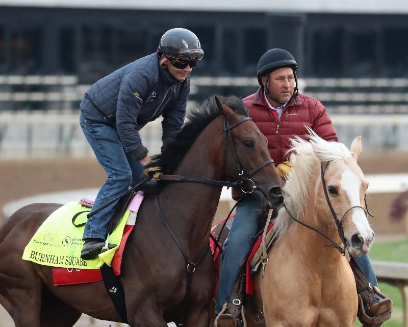 A detailed shot of Bob Baffert, a famous horse trainer, observing a horse during a morning workout at a racetrack