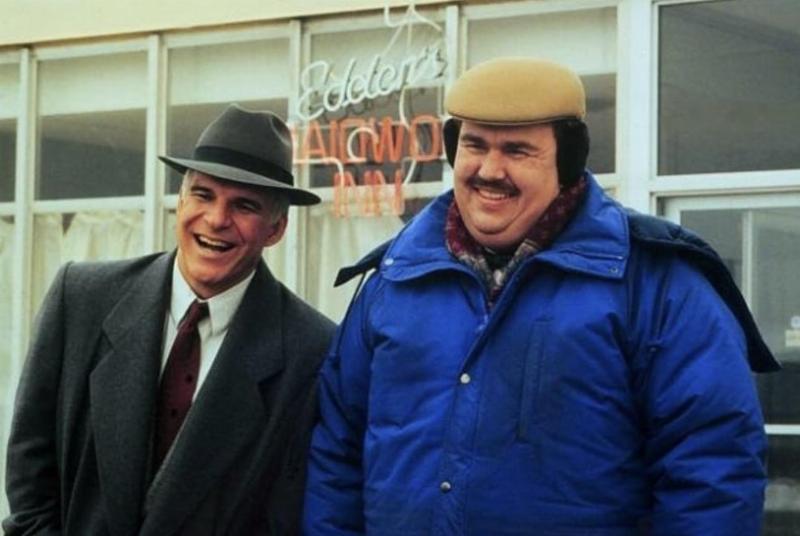 The character Del Griffith from Planes, Trains and Automobiles looking tired on an airplane, a reference to the 'my dogs are barking' scene.