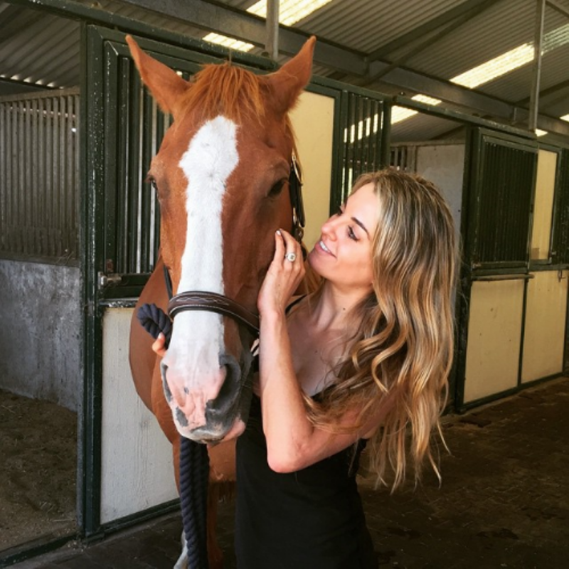 A focused horse and rider receiving instruction from a trainer in an outdoor arena, showcasing horse stables training.