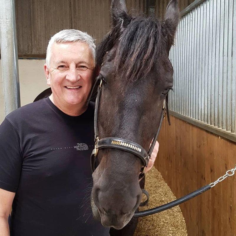 A female executive having a quiet moment of connection with a horse, gently touching its forehead, symbolizing trust and communication in horse leadership training.