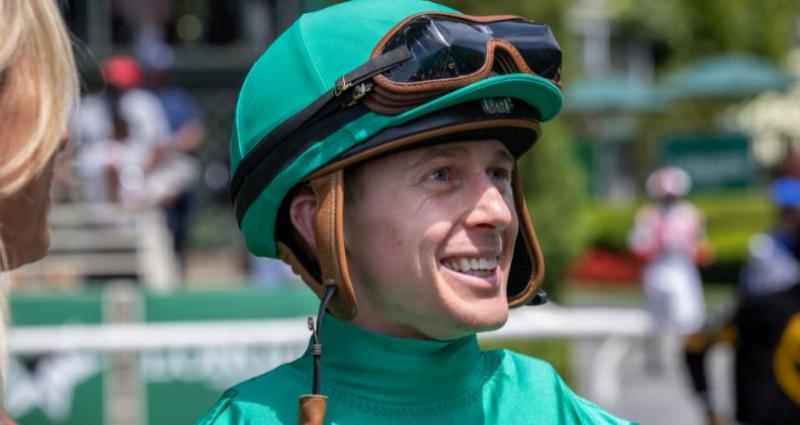 A dramatic photo of several thoroughbred horses and their jockeys neck and neck as they cross the finish line at Parx Racing, capturing the excitement of the sport.