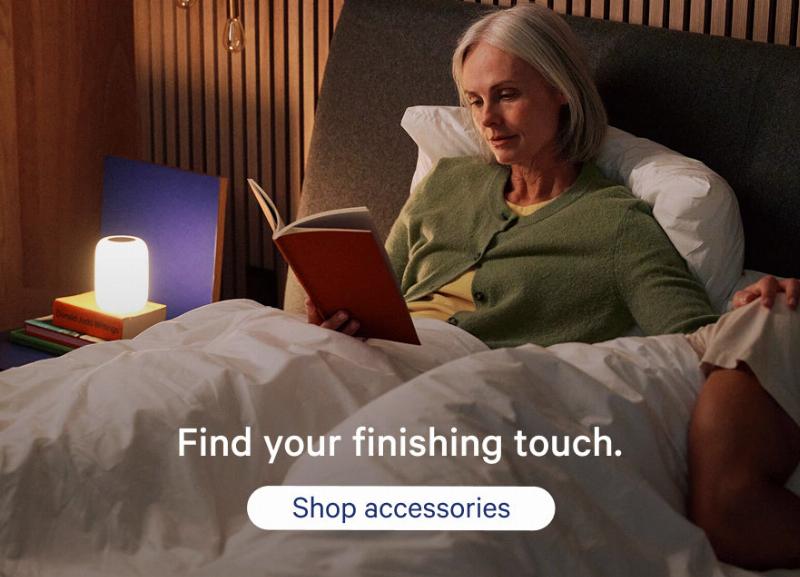 Alt text: A person sitting comfortably on a couch, reading a book about dog raising, with a happy dog resting at their feet.