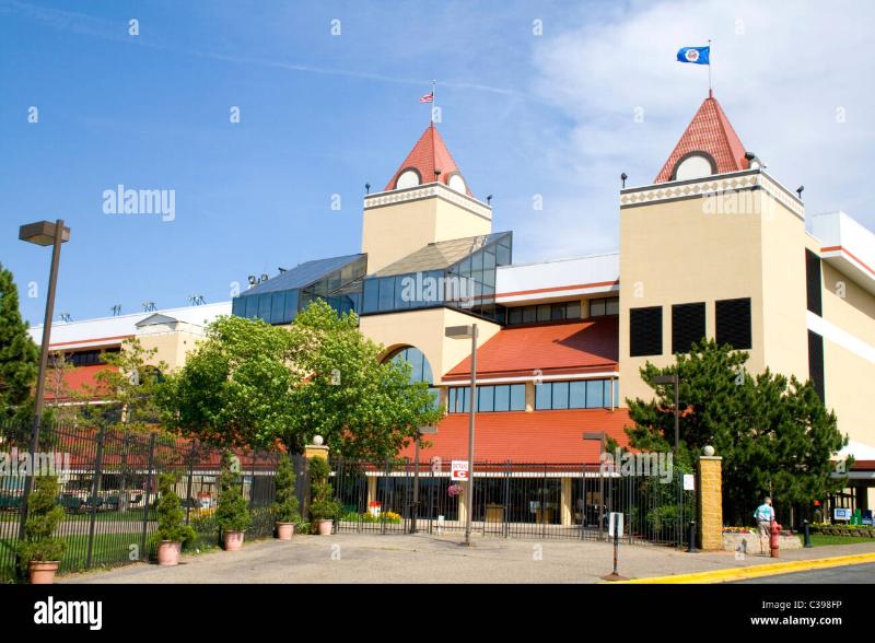 A stunning panoramic view of Red Mile horse racing in Lexington, showing a harness race in progress on the iconic red clay track with the historic grandstand in the background.