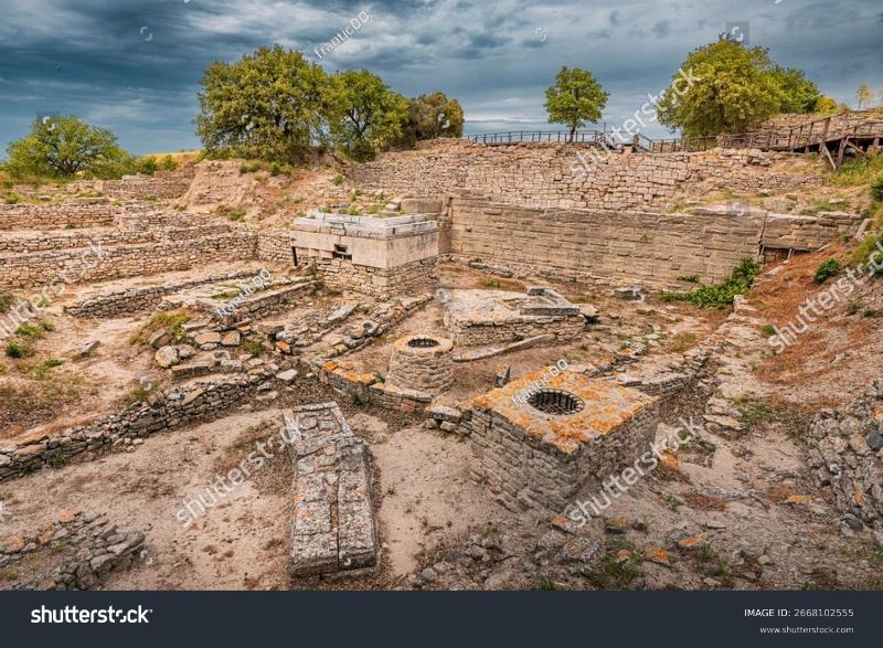 Archaeological ruins of the ancient city of Troy in modern-day Turkey, showing the layers of history under a clear blue sky.